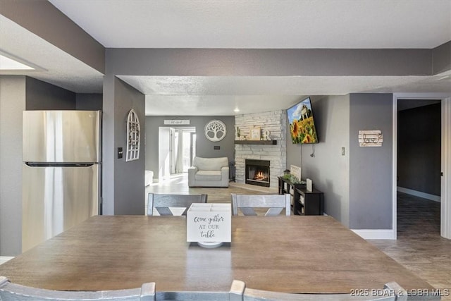 dining area with hardwood / wood-style flooring and a stone fireplace