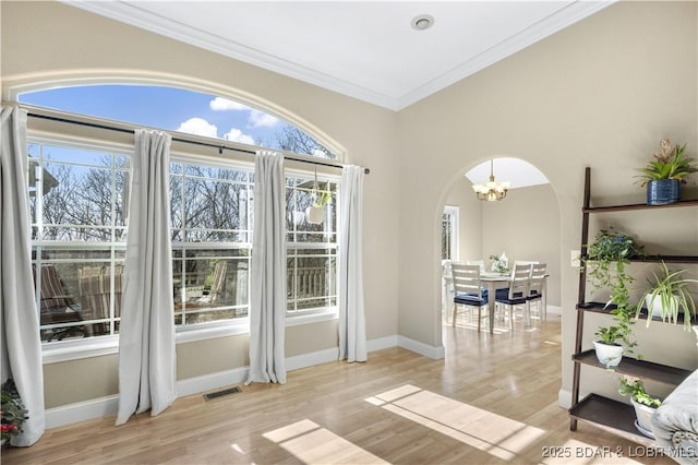 doorway to outside with light hardwood / wood-style flooring, crown molding, and a notable chandelier