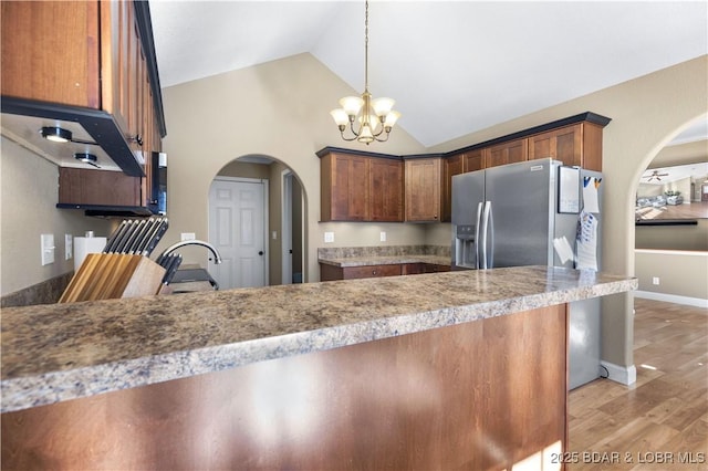 kitchen with a notable chandelier, hanging light fixtures, light wood-type flooring, sink, and stainless steel fridge