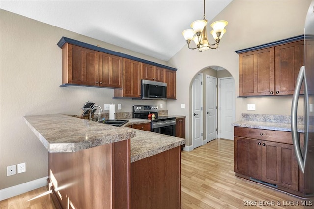 kitchen featuring stainless steel appliances, light hardwood / wood-style floors, sink, hanging light fixtures, and vaulted ceiling