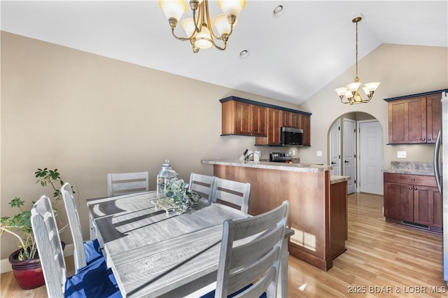 dining space featuring light hardwood / wood-style flooring, lofted ceiling, and an inviting chandelier