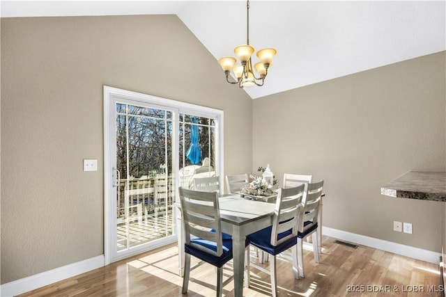 dining room with wood-type flooring, a chandelier, and high vaulted ceiling