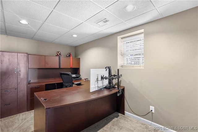 office space with a paneled ceiling and light carpet