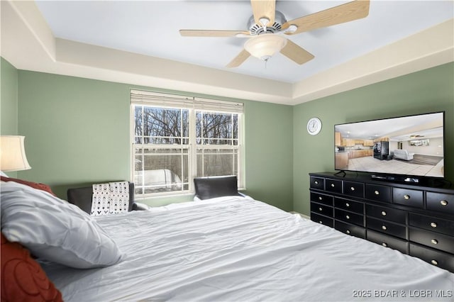 bedroom with ceiling fan and a tray ceiling