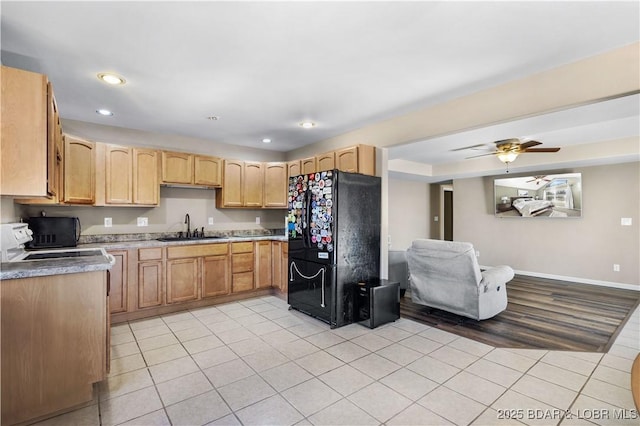 kitchen featuring light brown cabinets, ceiling fan, sink, light tile patterned floors, and black fridge