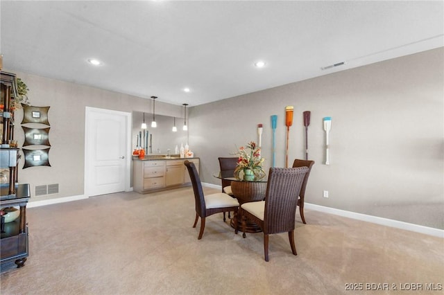 dining room featuring sink and light carpet