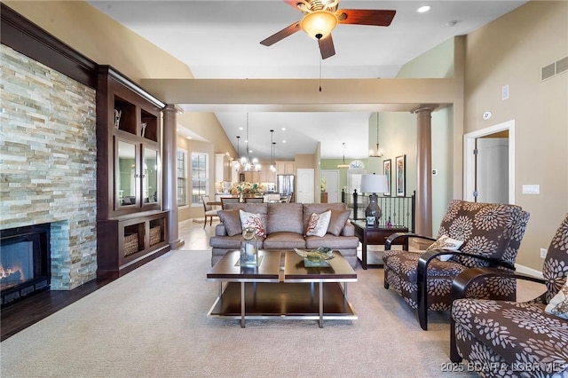 carpeted living room featuring decorative columns, ceiling fan with notable chandelier, a fireplace, and lofted ceiling