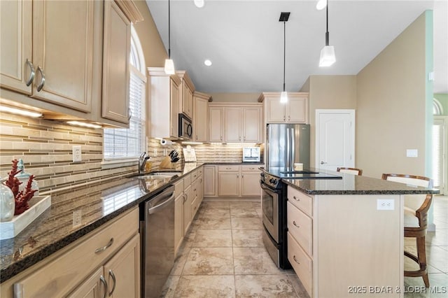 kitchen featuring sink, decorative light fixtures, appliances with stainless steel finishes, and a kitchen breakfast bar