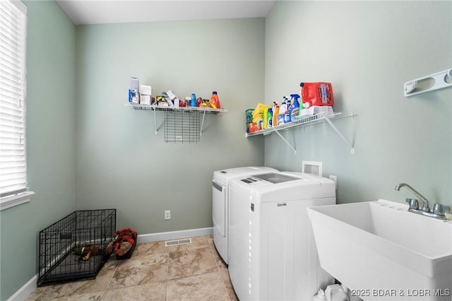 clothes washing area featuring sink, washing machine and clothes dryer, and plenty of natural light