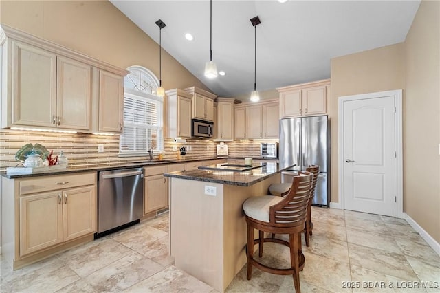 kitchen with a center island, appliances with stainless steel finishes, hanging light fixtures, dark stone countertops, and backsplash