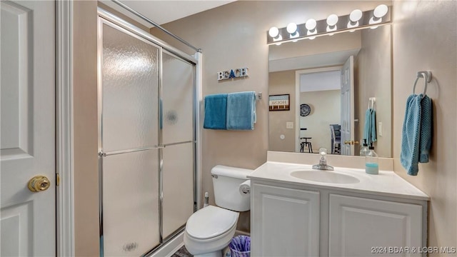 bathroom with vanity, toilet, and a shower with door