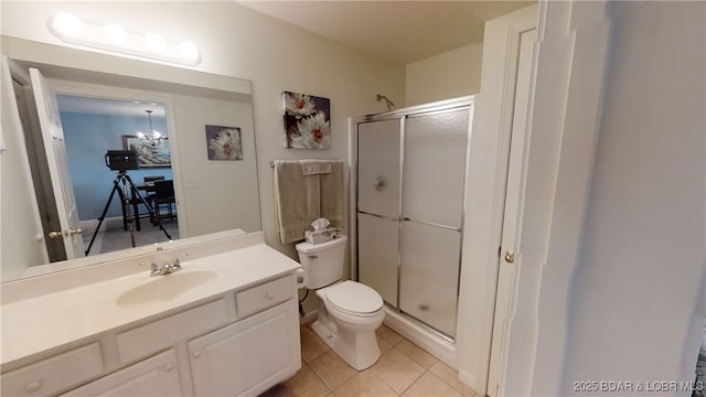 bathroom with tile patterned flooring, vanity, a shower with shower door, toilet, and a chandelier