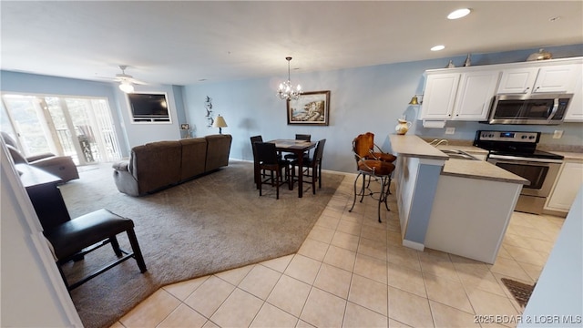 kitchen with a kitchen bar, hanging light fixtures, light tile patterned floors, appliances with stainless steel finishes, and white cabinets