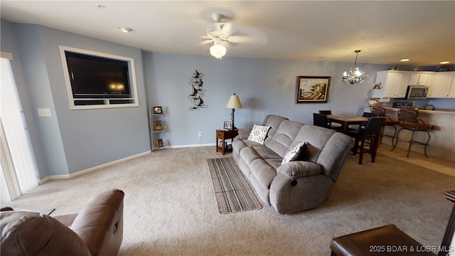 carpeted living room with ceiling fan with notable chandelier