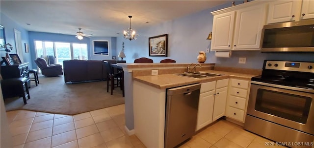 kitchen featuring pendant lighting, appliances with stainless steel finishes, kitchen peninsula, and white cabinets