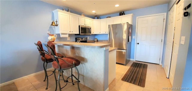 kitchen featuring appliances with stainless steel finishes, a breakfast bar, white cabinets, and kitchen peninsula