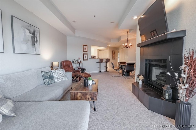 carpeted living room with a tile fireplace and an inviting chandelier