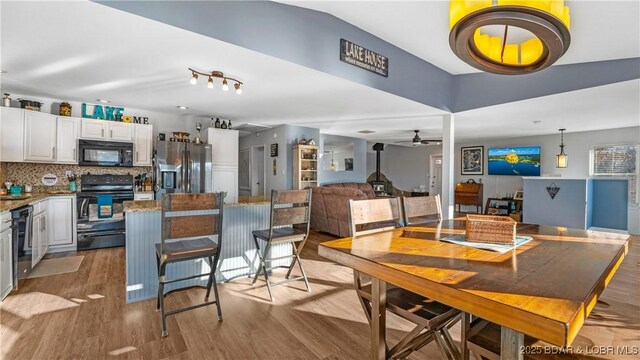 dining area featuring light wood-type flooring, ceiling fan, and a wood stove