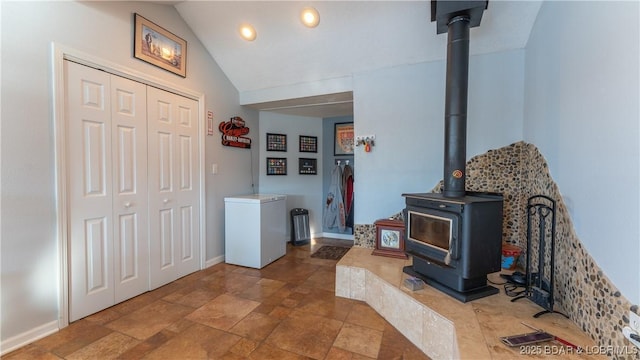 interior space featuring lofted ceiling and a wood stove