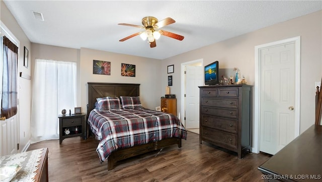 bedroom featuring dark wood-type flooring, ceiling fan, and a textured ceiling