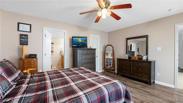 bedroom with ceiling fan, ensuite bathroom, wood-type flooring, and a textured ceiling