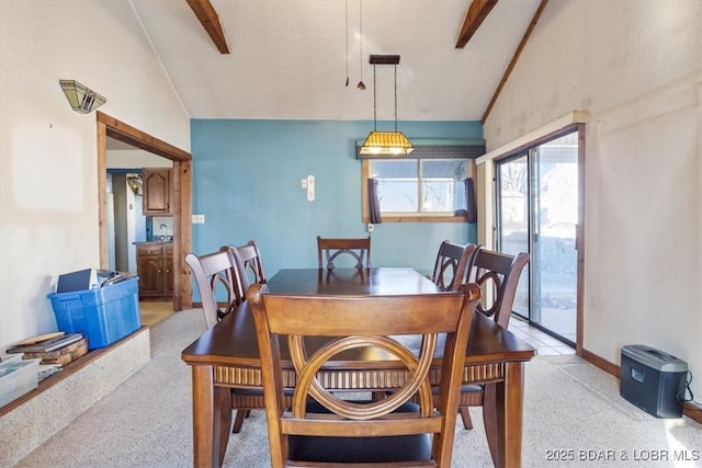 dining space featuring vaulted ceiling with beams and light colored carpet