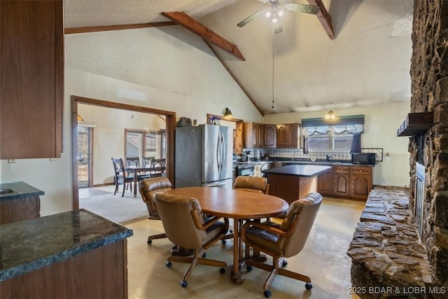 dining space featuring ceiling fan, high vaulted ceiling, a textured ceiling, a stone fireplace, and beamed ceiling