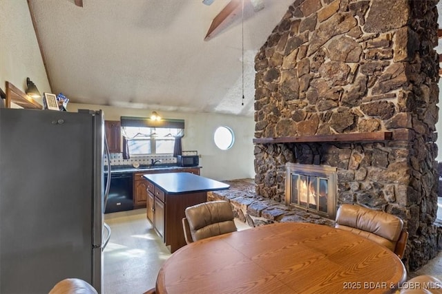 kitchen featuring lofted ceiling, black dishwasher, stainless steel fridge, decorative backsplash, and a textured ceiling