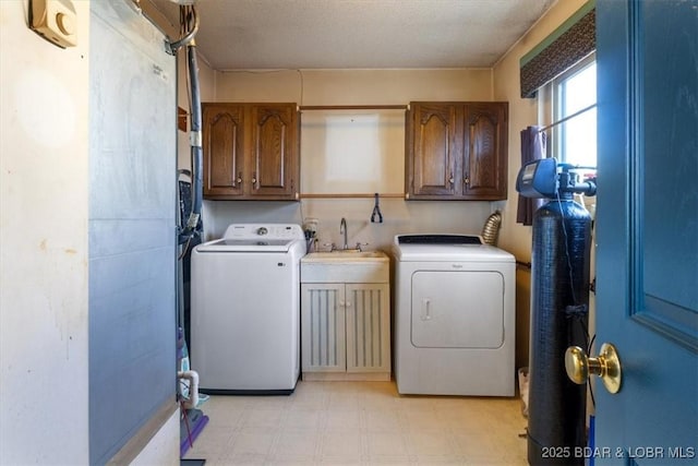 clothes washing area featuring cabinets, sink, washing machine and dryer, and a textured ceiling