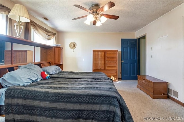 carpeted bedroom featuring ceiling fan and a textured ceiling