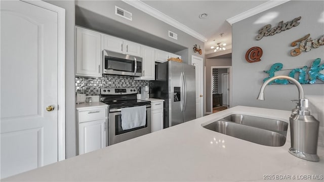 kitchen featuring sink, white cabinetry, stainless steel appliances, ornamental molding, and decorative backsplash