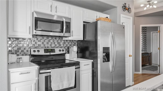 kitchen featuring white cabinetry, stainless steel appliances, crown molding, and tasteful backsplash