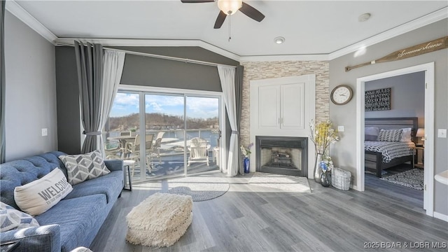 living room with ornamental molding, lofted ceiling, a fireplace, and hardwood / wood-style floors