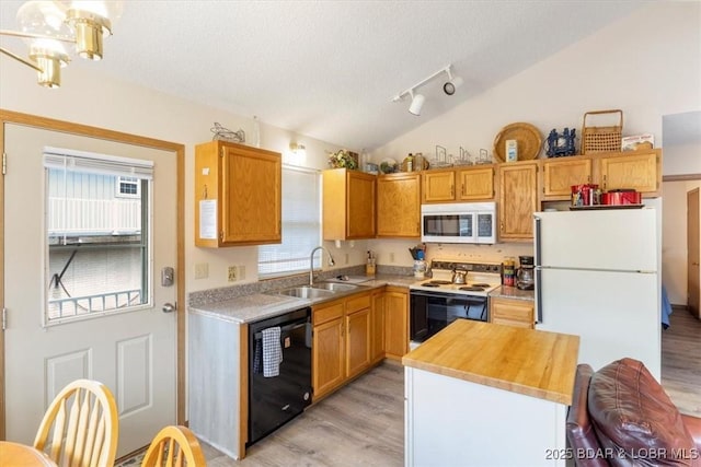 kitchen with sink, white appliances, a wealth of natural light, vaulted ceiling, and light wood-type flooring