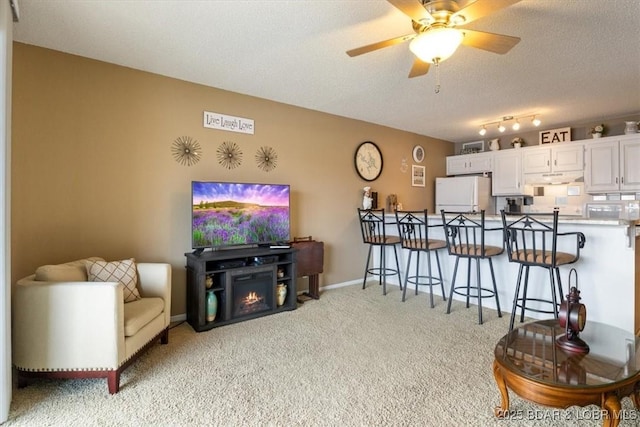 living room with ceiling fan, light carpet, and a textured ceiling