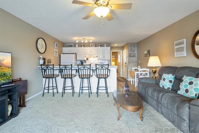 living room featuring light carpet, ceiling fan, and a textured ceiling