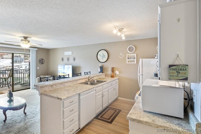 kitchen with white cabinetry, sink, light hardwood / wood-style floors, kitchen peninsula, and white appliances