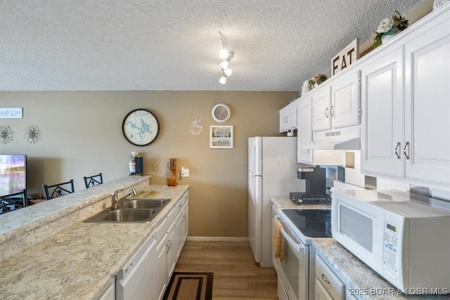 kitchen with sink, white appliances, white cabinetry, light hardwood / wood-style floors, and a textured ceiling