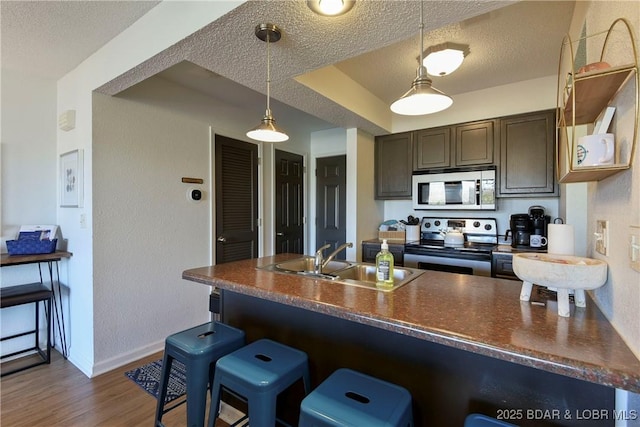 kitchen featuring appliances with stainless steel finishes, pendant lighting, sink, a breakfast bar area, and a textured ceiling