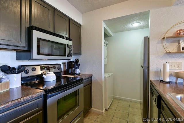 kitchen featuring dark brown cabinetry, light tile patterned floors, stainless steel appliances, and a textured ceiling