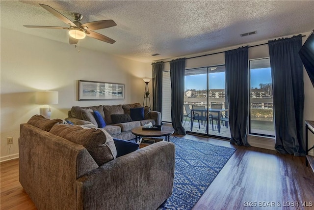 living room with ceiling fan, hardwood / wood-style flooring, and a textured ceiling