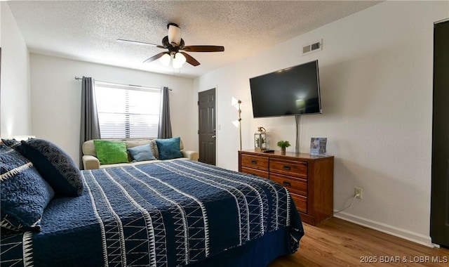 bedroom with hardwood / wood-style flooring, a textured ceiling, and ceiling fan