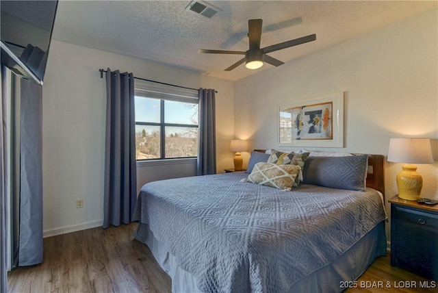 bedroom featuring a textured ceiling, dark wood-type flooring, and ceiling fan