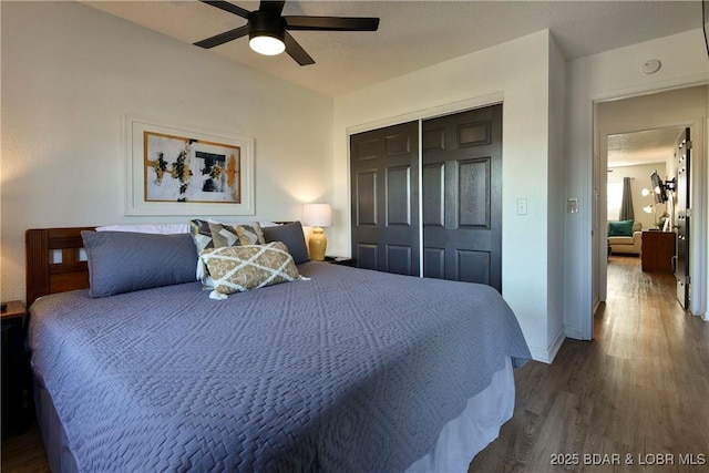 bedroom with dark wood-type flooring, ceiling fan, and a closet