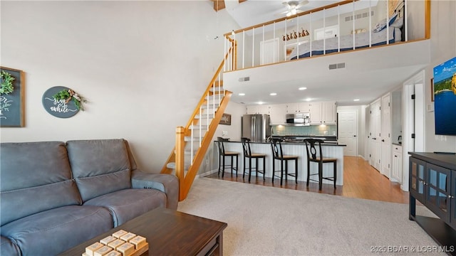 living room with a towering ceiling and light hardwood / wood-style flooring