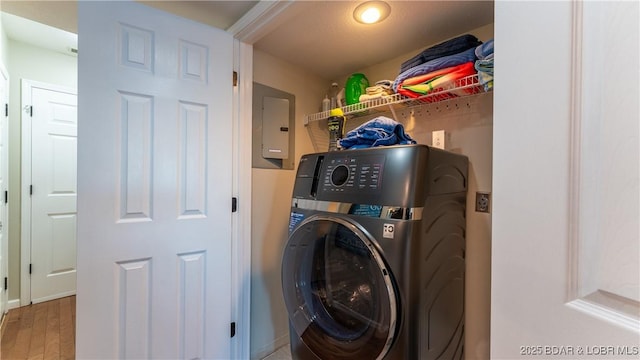 clothes washing area with hardwood / wood-style flooring, washer / dryer, and electric panel