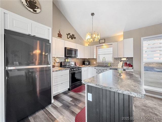 kitchen featuring a kitchen island, stainless steel fridge, black range with gas cooktop, and white cabinets