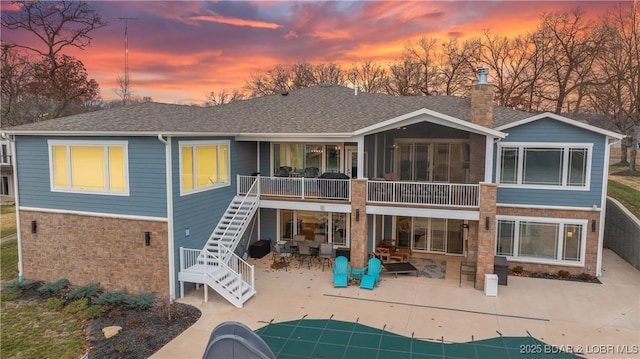 back house at dusk with a covered pool and a patio