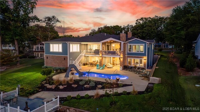 back house at dusk featuring a balcony and a patio