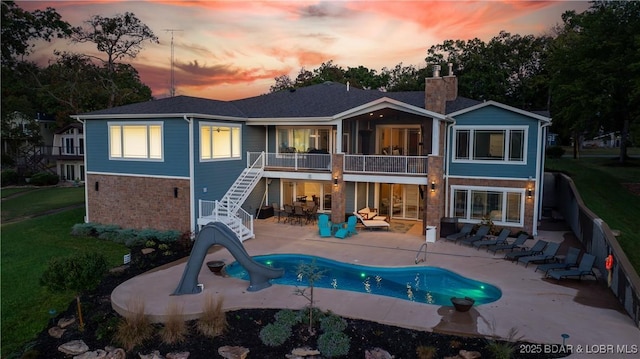 back house at dusk featuring a patio and a balcony